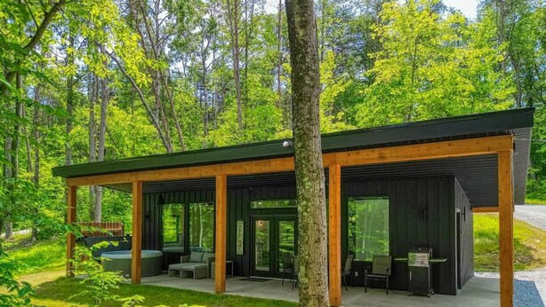 Una moderna baita con patio coperto, posti a sedere all'aperto e zona barbecue.