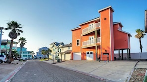 A multi-story building with a red facade, a garage, and a balcony.