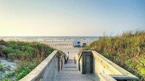 A wooden boardwalk leading to a beach with a dune and a dune buggy parked on the sand. - Beach Boardwalk, Pool Access & Ocean Views Coral Reef by Avantstay (Port Aransas)