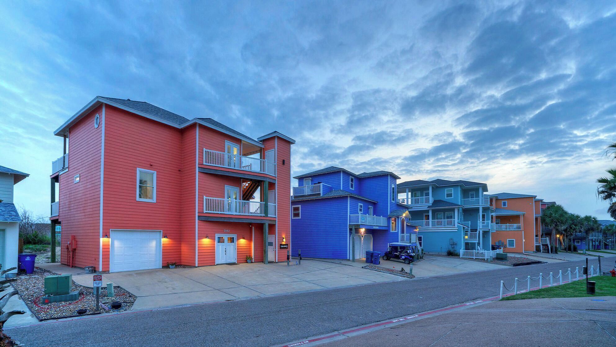 Une rangée d’immeubles résidentiels à plusieurs étages, dotés de balcons, avec une allée pavée et un ciel dégagé.