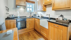 Une cuisine avec des meubles de rangement en bois, une cuisinière, un four à micro-ondes et un évier.