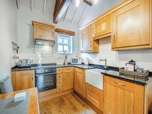 A kitchen with wooden cabinets, a stove, a microwave, and a sink.