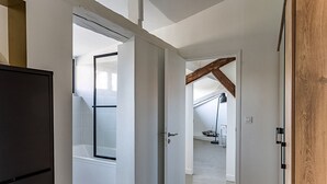 Um corredor leva a um quarto com teto inclinado e um claraboia visível.