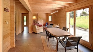 A wooden interior with a dining area, a sofa, and a staircase leading to another room.