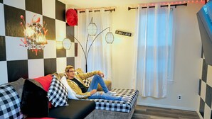 A modern living room with a checkered wall, a sofa, and a red accent cushion. - Trendy Downtown Nashua Getaway: Checkers-Themed 1 Bed/1 Bath! (Nashua)