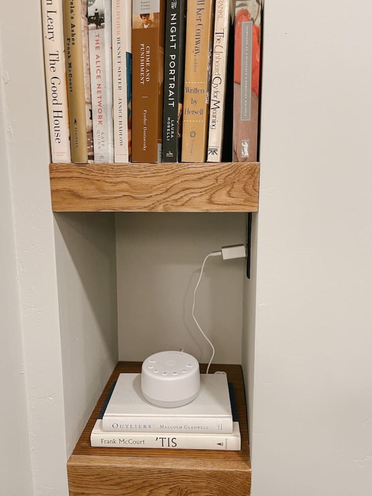Ein Bücherregal mit Büchern und einem weißen Gerät auf einer Holztrennwand.