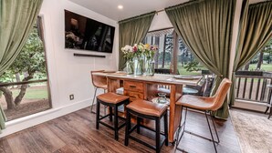 A dining area with a wooden table, four chairs, and a TV mounted on the wall.