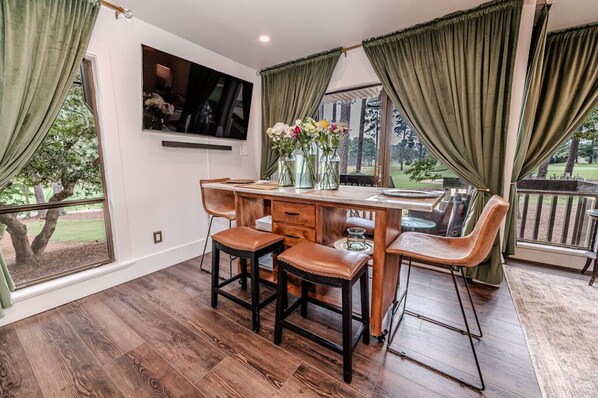 Un coin repas avec une table en bois, quatre chaises et un téléviseur fixé au mur.