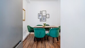 A dining area with a wooden table, green upholstered chairs, and framed artwork on the wall. - Beautiful Flat Near the Center 11 min  (London)