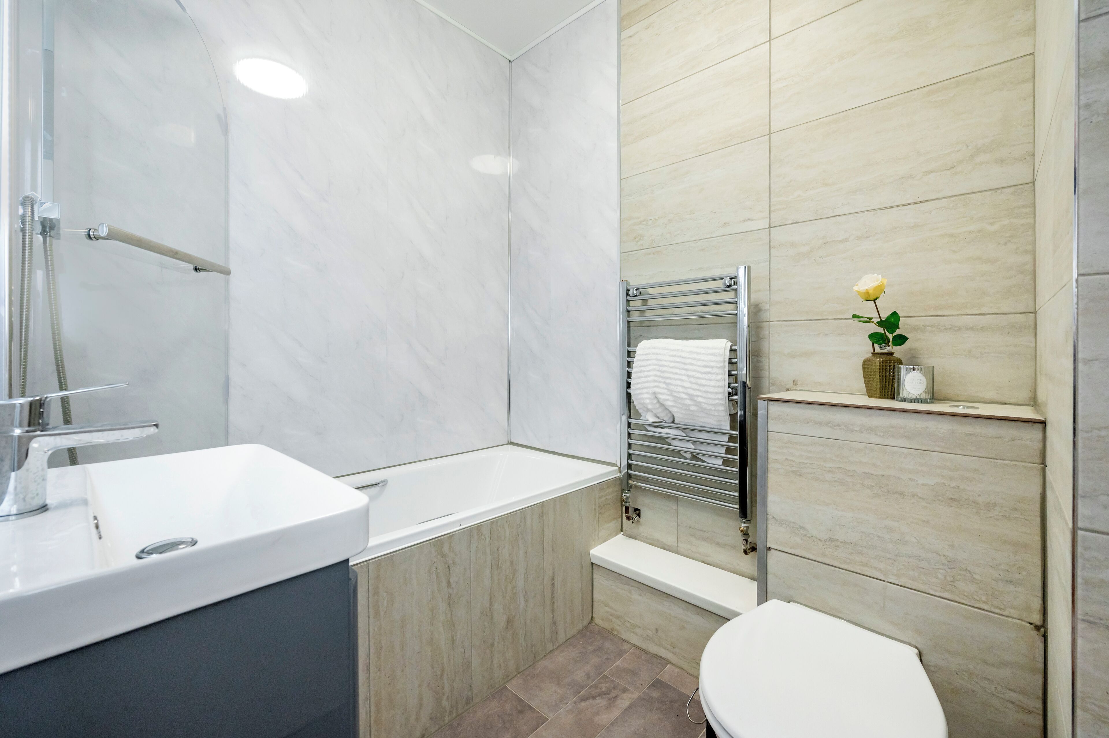 Ein modernes Badezimmer mit einem weißen Waschbecken, einer Badewanne und einer Toilette.