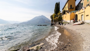 Une vue sur le lac, avec un quai pour bateaux, une rive rocheuse et des bâtiments dotés de balcons.