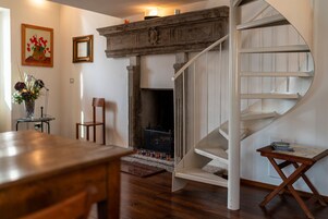A modern interior with a fireplace, a wooden dining table, and a spiral staircase.
