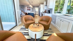 A modern kitchen with white cabinets, a central island, and a view of the outdoors. - Green Lake Getaway Lakefront Hot Tub Kayak SUP (Interlochen)