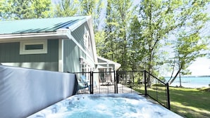 A hot tub in front of a house with a deck and a view of a lake. - Green Lake Getaway Lakefront Hot Tub Kayak SUP (Interlochen)
