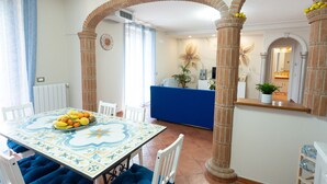 A dining area with a table set for four, a blue cushioned bench, and a blue counter. - Casa Francese Relax - An oasis of well-being not far from the sea (Tramonti)