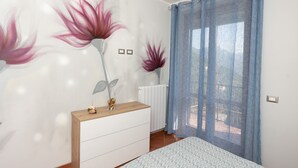 A bedroom with a bed, a wooden bedside table with a vase, and a wall with floral artwork. - Casa Francese Relax - An oasis of well-being not far from the sea (Tramonti)