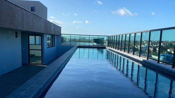 A rooftop infinity pool with clear views of the city skyline, surrounded by glass railings and modern architecture.