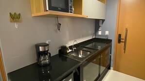 A compact kitchen with a microwave, coffee maker, and a refrigerator.