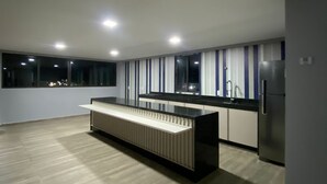 A modern kitchen with a central island, built-in appliances, and a large window providing a view of the city at night.