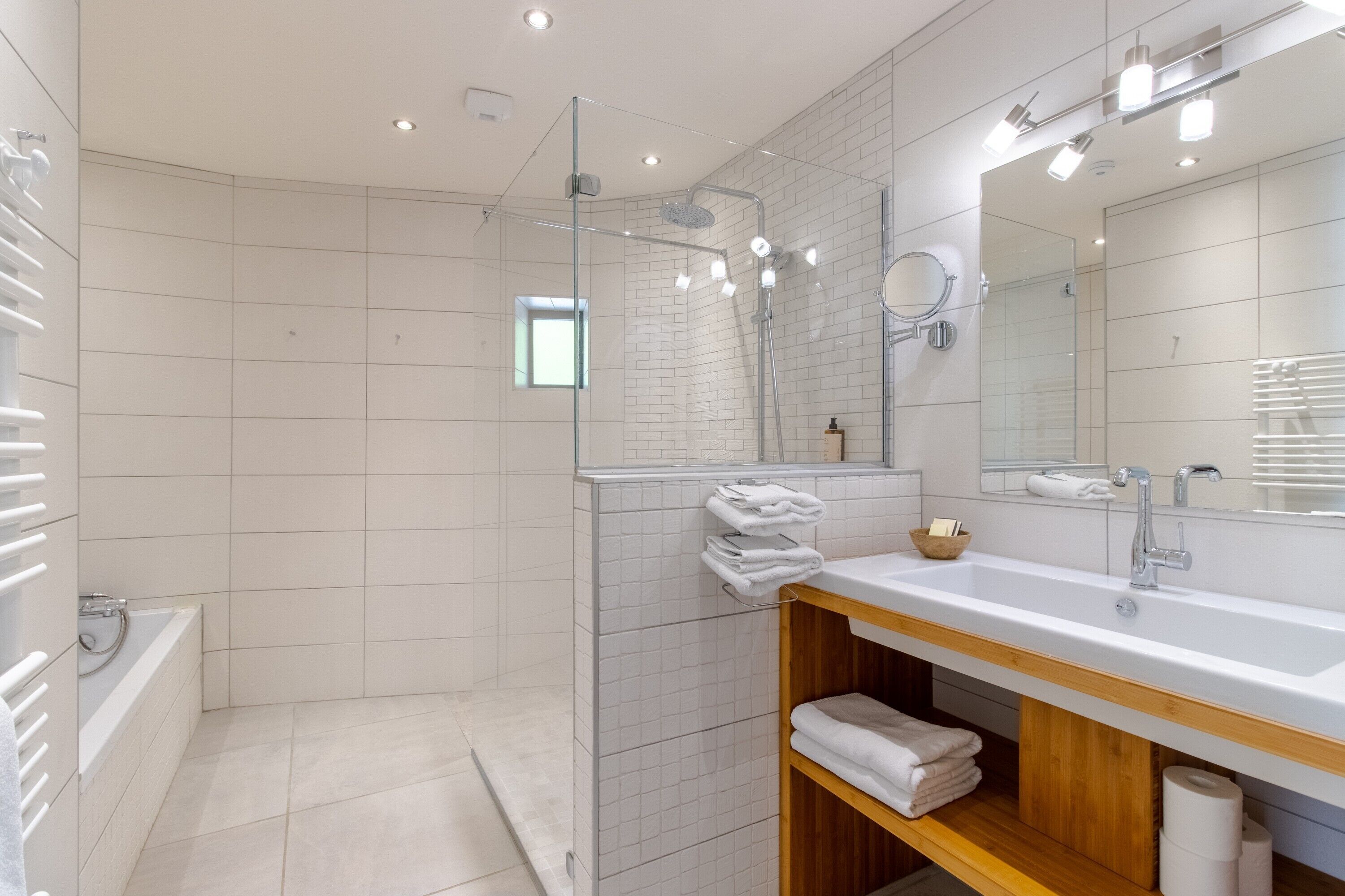 Une salle de bain moderne avec une douche à parois de verre, un grand miroir et un lavabo blanc.