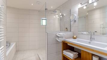 Une salle de bain moderne avec une douche à parois de verre, un grand miroir et un lavabo blanc.
