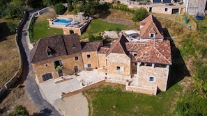 A large stone building with multiple rooms, a swimming pool, and a well-maintained lawn.