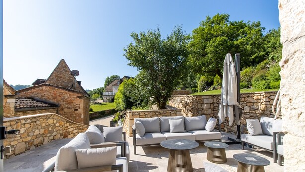 An outdoor patio area with stone walls, a stone roof, and a large tree providing shade. - Holiday Home 'Gite Les Hauts De L'ouysse' with Private Pool, Wi-Fi and Air Conditioning (Lacave)