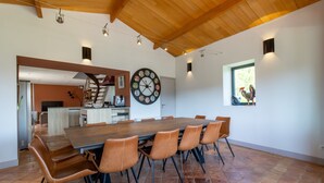 A spacious dining area with a large wooden table and leather chairs, a wall clock, and a window with a view. - Holiday Home 'Gite Les Hauts De L'ouysse' with Private Pool, Wi-Fi and Air Conditioning (Lacave)