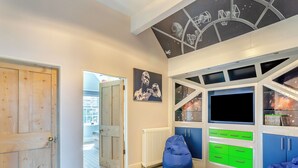 A room with a wooden door, a radiator, a blue bean bag, and a wall with a space-themed mural. - 6 bedroom accommodation in Old Quarrington, near Durham (Old Quarrington, near Durham)
