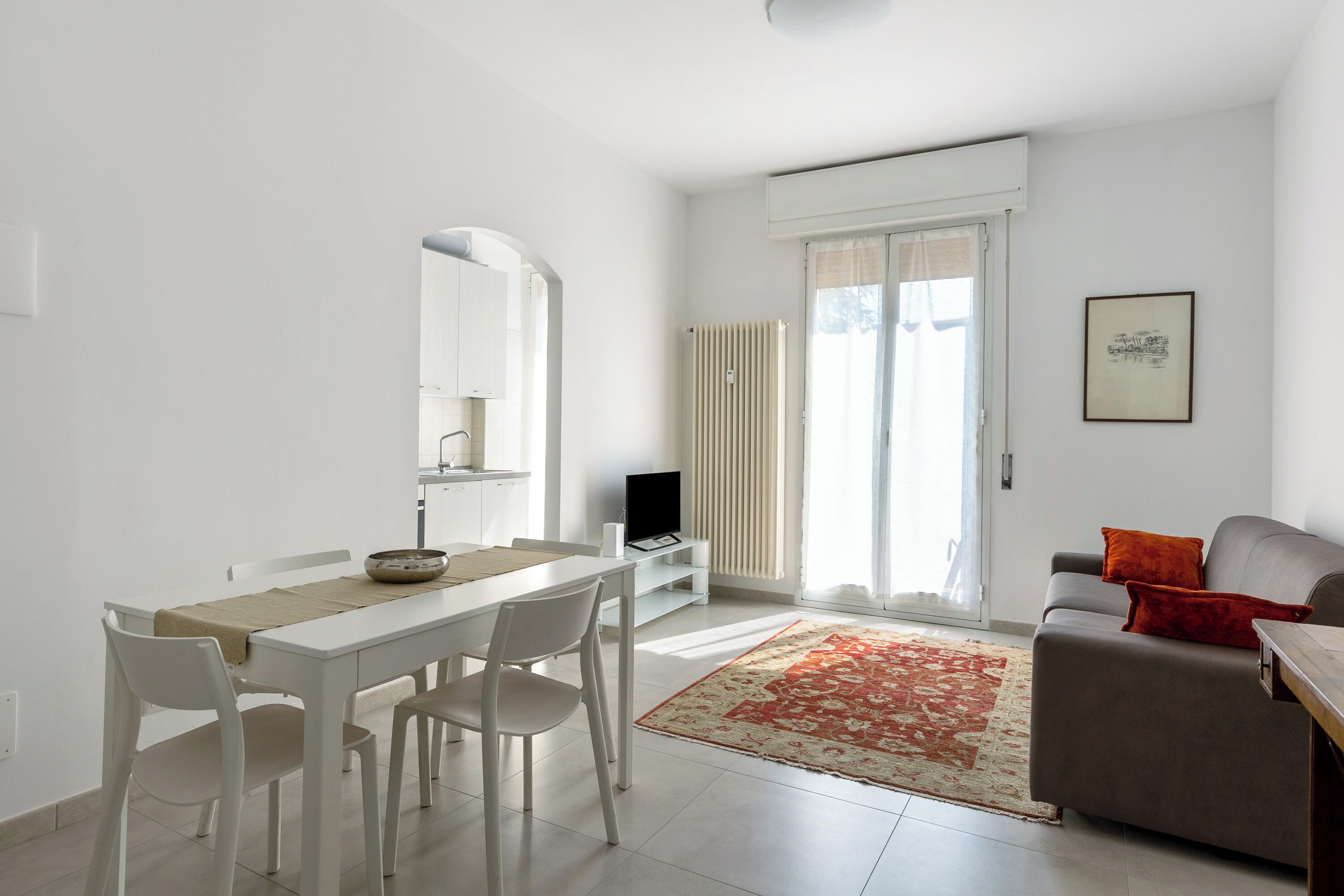 A modern living room with a dining area, a sofa, and a television.