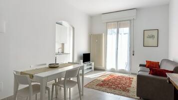 A modern living room with a dining area, a sofa, and a television.