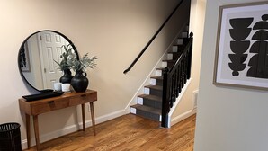 A wooden console table with a mirror, a vase with plants, and a black tray.