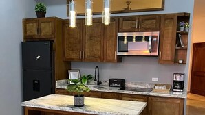 Une cuisine moderne dotée d’un îlot central, de meubles en bois, d’appareils électroménagers en acier inoxydable et de luminaires suspendus.