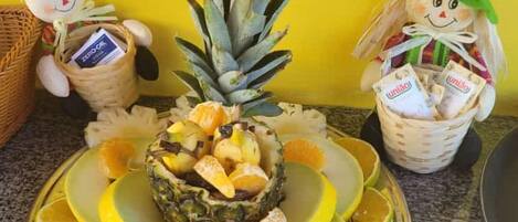 A fruit platter with a pineapple, oranges, and a basket of corn.