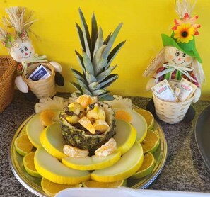 A fruit platter with a pineapple, oranges, and a basket of corn. - Pousada e Balneário Recanto dos Passaros BRB (Barreirinhas)
