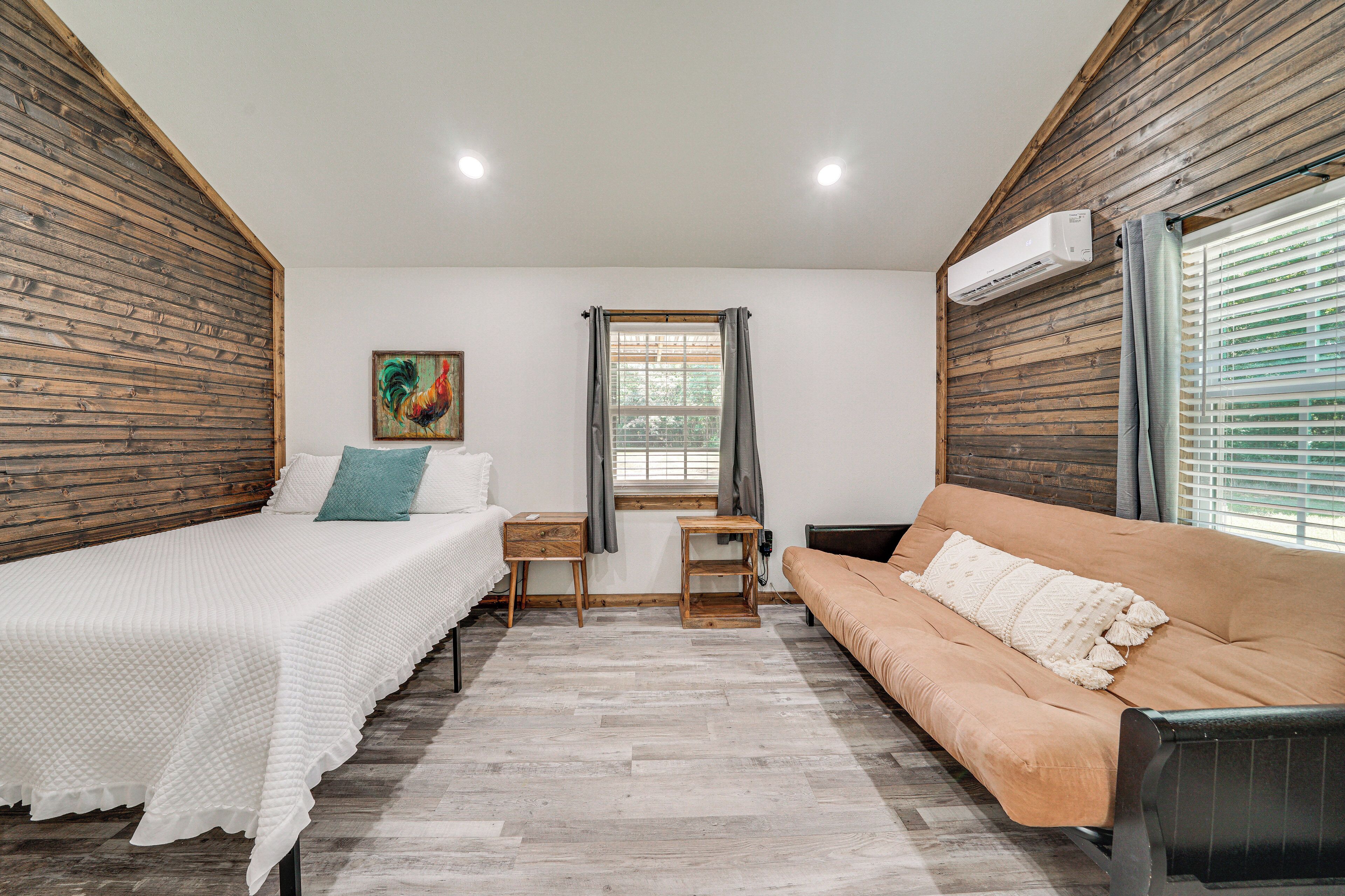 Un dormitorio con una cama, un sofá, una mesita y una ventana con cortinas.