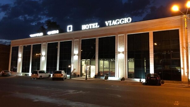 Un hôtel doté d’une façade moderne, de grandes fenêtres et d’un parking où sont stationnées plusieurs voitures.