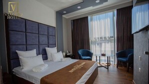 Une chambre d’hôtel avec un grand lit, une petite table, deux chaises et un téléviseur.