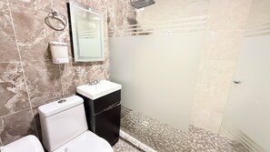 A bathroom with a toilet, sink, mirror, and shower area. - Lomas Altas Tonala Céntrico 6 (Tonalá)