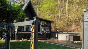 A cabin with a deck, a hot tub, and a fenced yard. - Crescent Moon: Hot Tub, Arcade, Dogs, EV charger, Minutes from Shenandoah (Luray)