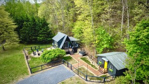 A cabin with a deck, surrounded by dense forest. - Crescent Moon: Hot Tub, Arcade, Dogs, EV charger, Minutes from Shenandoah (Luray)