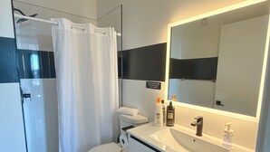 Een moderne badkamer met douche, toilet en wastafel.