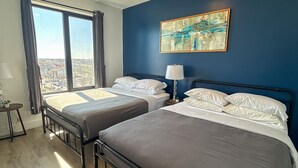 Een slaapkamer met twee bedden, een groot raam en een schilderij aan de muur.