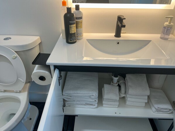 Un baño con inodoro, lavamanos y perchero para toallas.