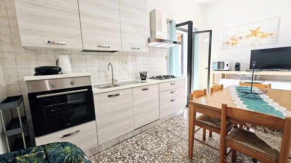 Una cucina moderna con forno integrato, piano cottura a gas e zona pranzo con tavolo e sedie.
