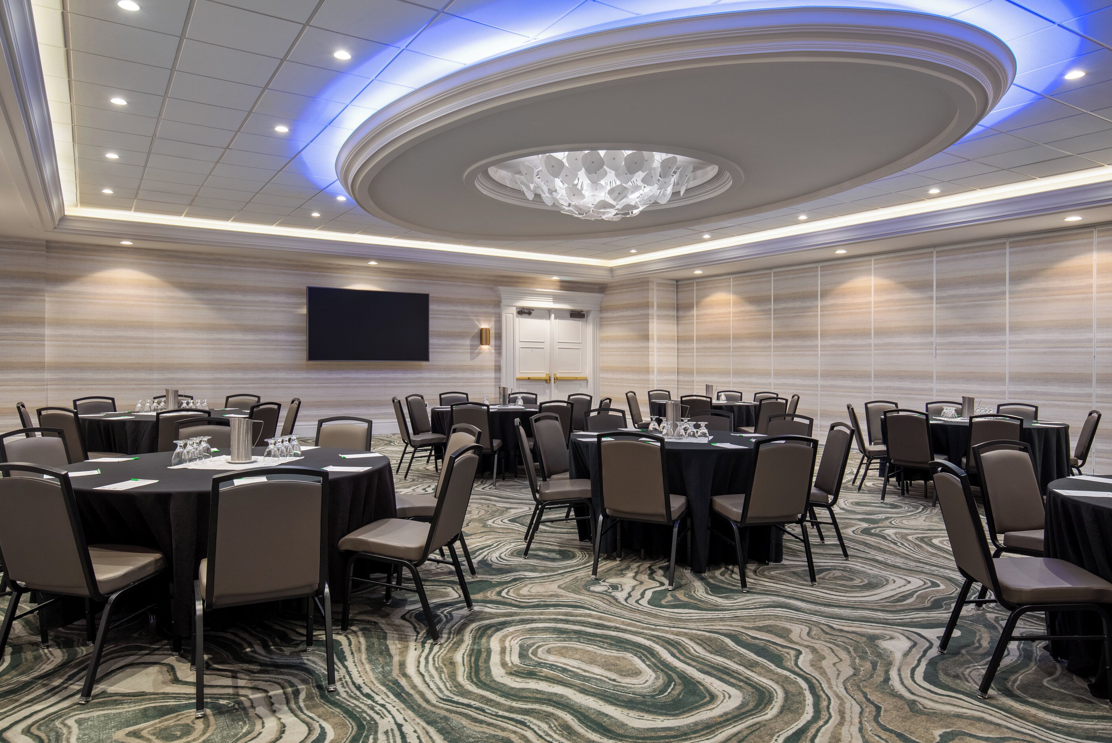 A conference room with round tables, chairs, and a large chandelier.
