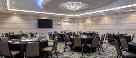 A conference room with round tables, chairs, and a large chandelier.