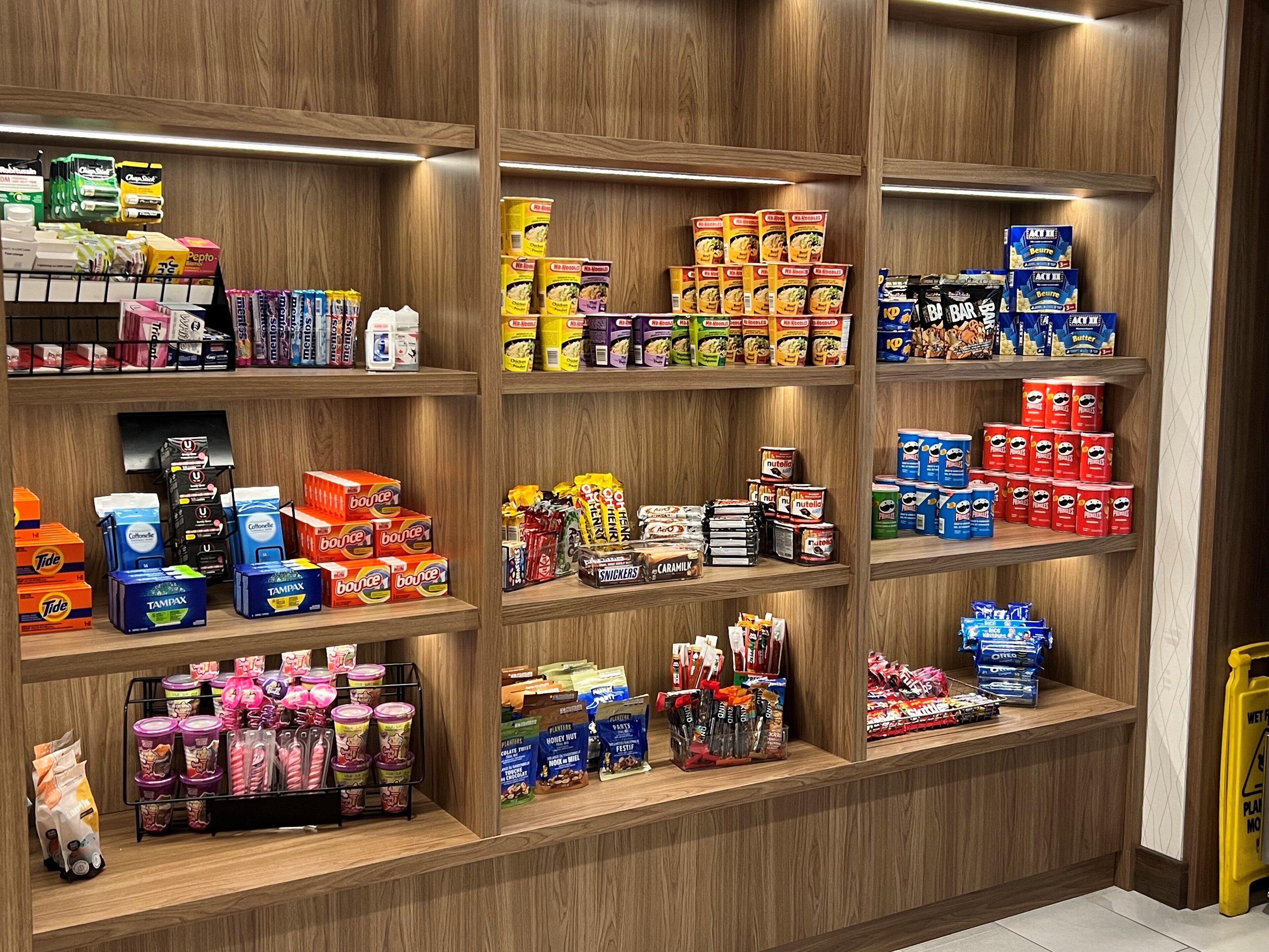 Un magasin bien organisé, doté de plusieurs étagères remplies d’une grande variété de produits, notamment des collations, des boissons et des articles ménagers.