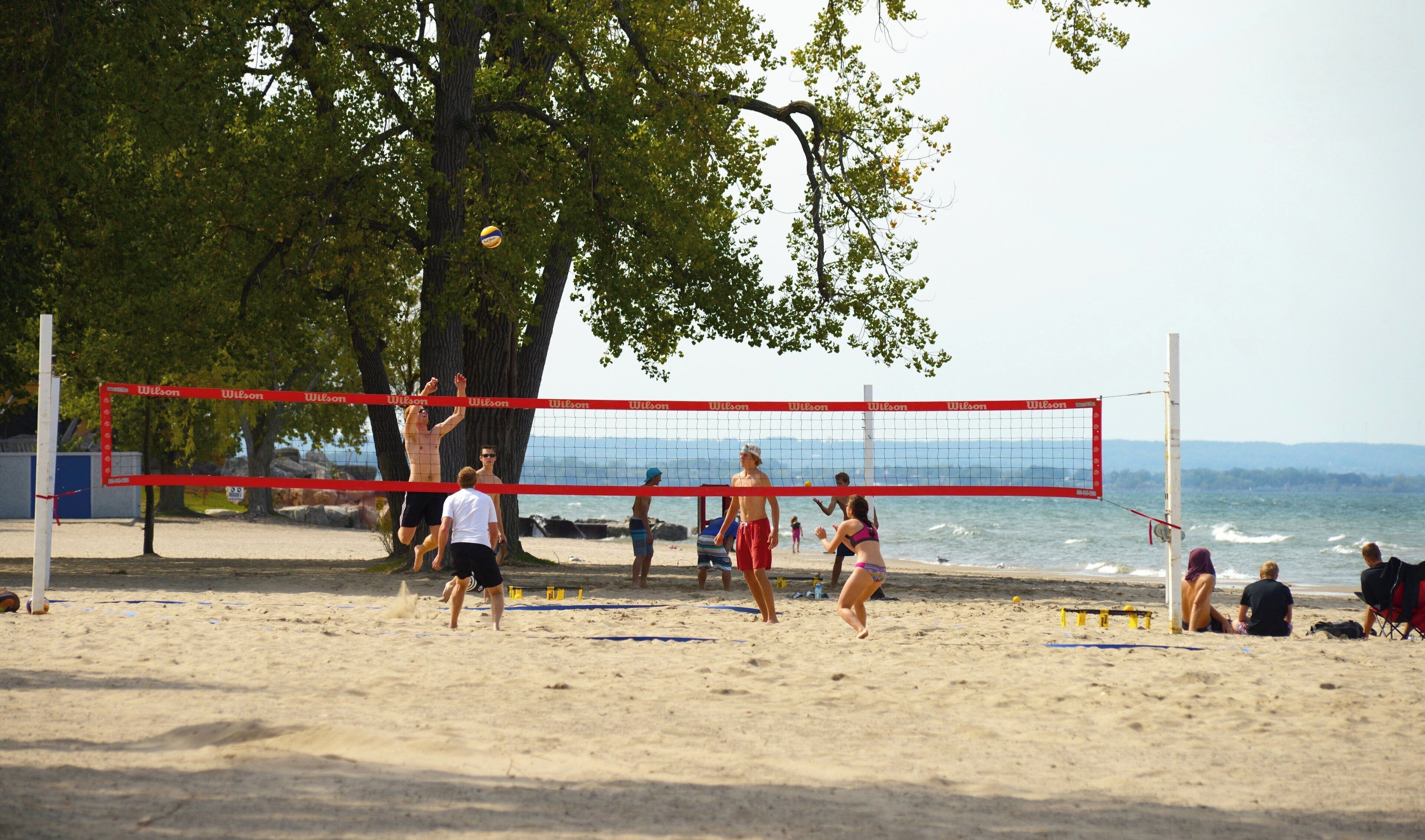 Een strandvolleybalwedstrijd met spelers en toeschouwers.