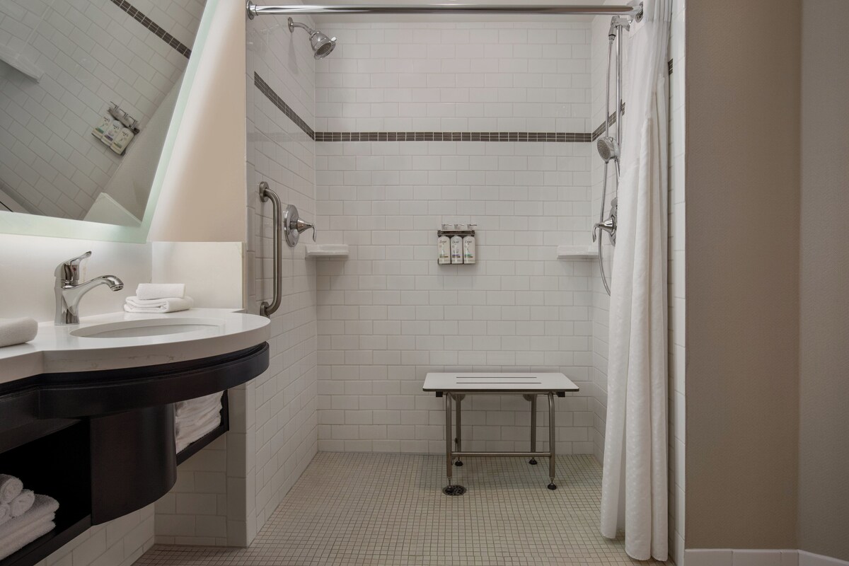 Een moderne badkamer met een witte wastafel, spiegel en douche.